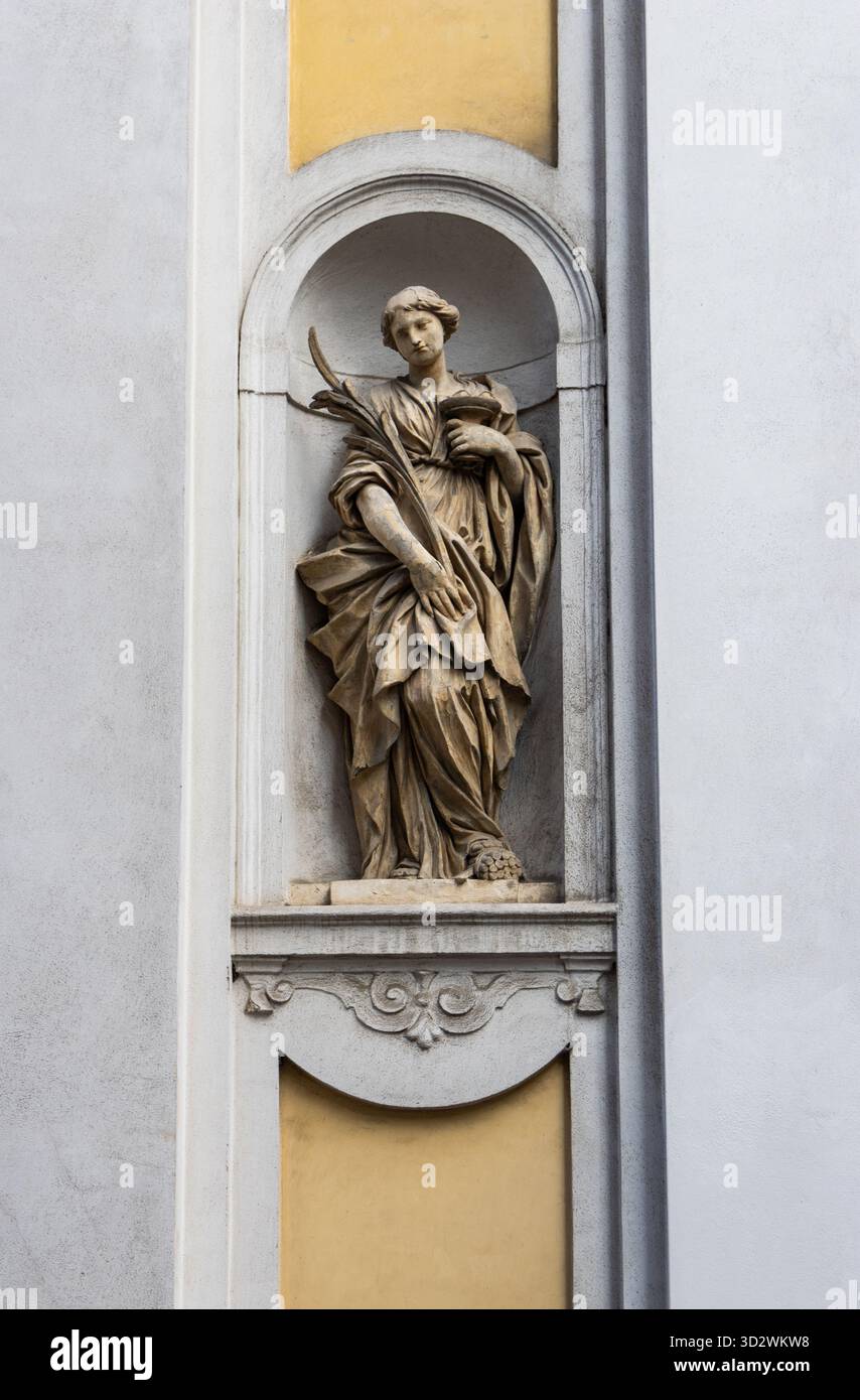 Sculpture de saint antique sculptée dans la façade de l'église représente évêque tenant le personnel symbolisant la spiritualité de la tradition de foi et la culture chrétienne italienne Banque D'Images