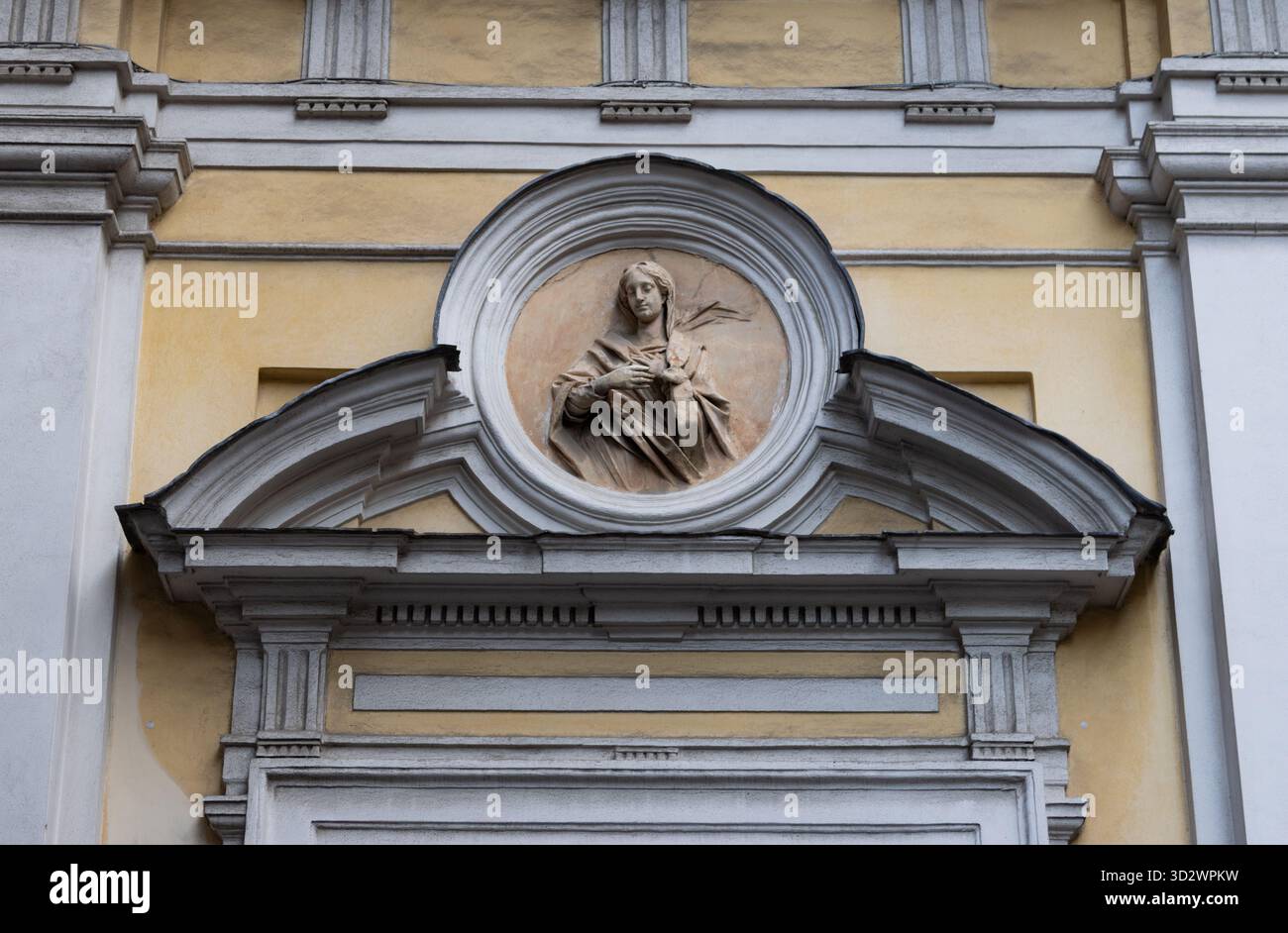 Sculpture en relief en pierre de la sainte féminine orne la façade de l'église italienne dans un cadre circulaire représentant l'art et la tradition patrimoniale de la dévotion catholique. Banque D'Images
