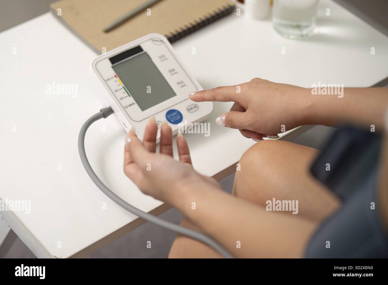 Une femme pointe vers un tensiomètre numérique, se concentrant sur la sensibilisation à la santé et le bien-être personnel Banque D'Images