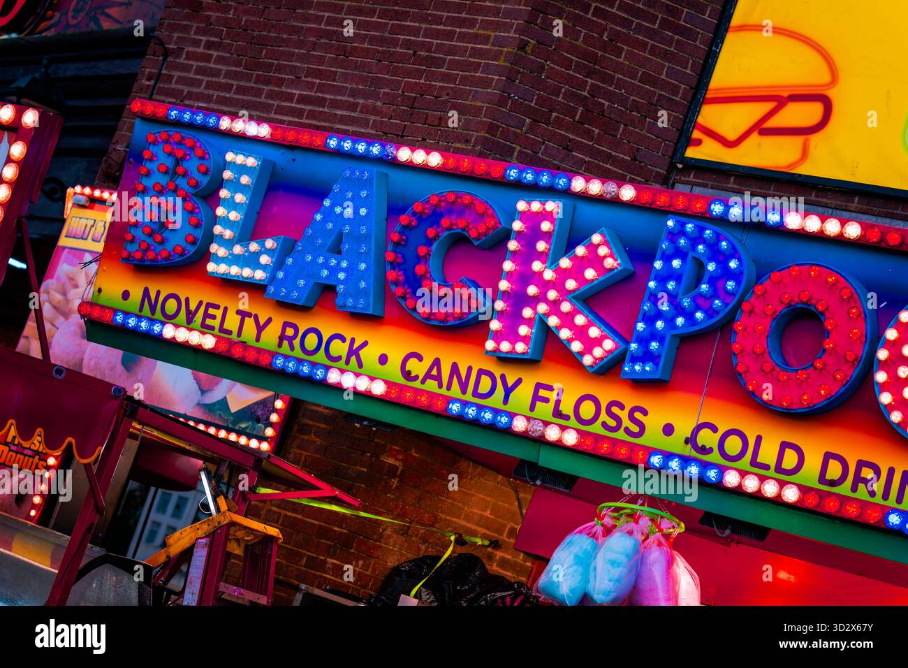 Un stand lumineux près du front de mer à Blackpool, Lancashire, Royaume-Uni. L'étal vend de la pierre de fantaisie, du fil dentaire de bonbon, des boissons, etc Banque D'Images