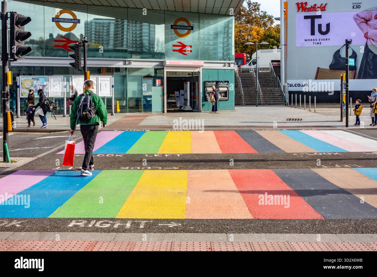 Un homme traverse la route par un passage piétonnier coloré peint aux couleurs de l'arc-en-ciel à Shepherd's Bush, Londres Banque D'Images