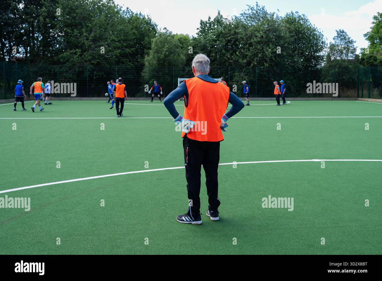 Groupe d'hommes seniors jouant au football marchant sur terrain artificiel Banque D'Images