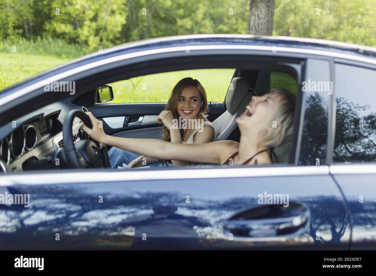 Deux femmes riant des conducteurs à la voiture souriant. Mignon jeune femme heureuse conduisant le véhicule de voiture Banque D'Images