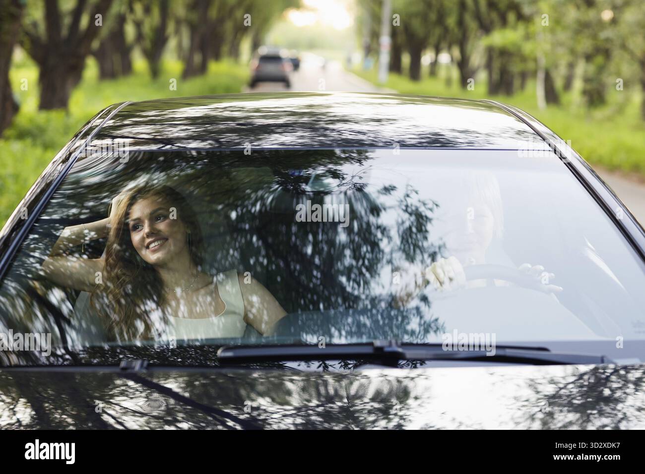 Deux femmes pilotes à la voiture souriant. Mignon jeune femme heureuse conduisant le pare-brise de véhicule de voiture Banque D'Images