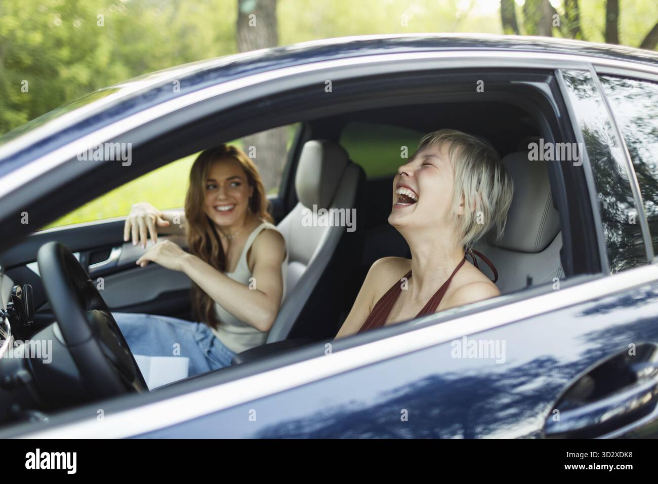 Deux femmes riant des conducteurs à la voiture souriant. Mignon jeune femme heureuse conduisant le véhicule de voiture Banque D'Images