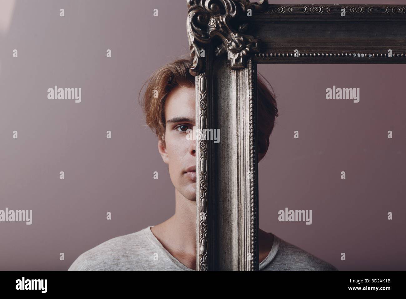 Jeune homme artiste millénaire avec les cheveux blonds sur le cadre doré partie de visage portrait Banque D'Images