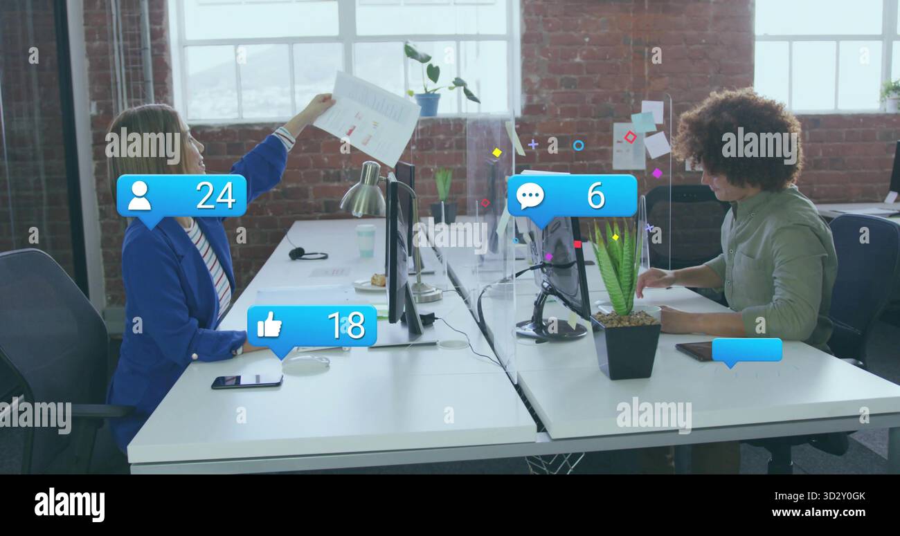 Les employés de bureau discutent de rapports imprimés entre deux moniteurs dans le bureau, avec des icônes de médias sociaux Banque D'Images