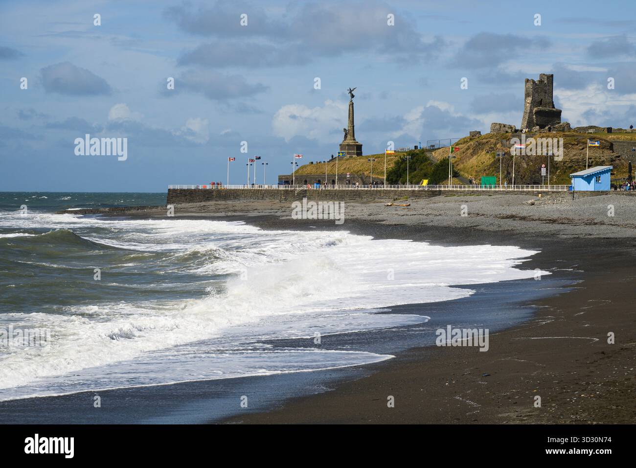 Aberystwyth, pays de Galles, Royaume-Uni - 1er septembre 2025 ; les vagues s'écrasent sur la plage sous le château et le mémorial d'Aberystwyth Banque D'Images