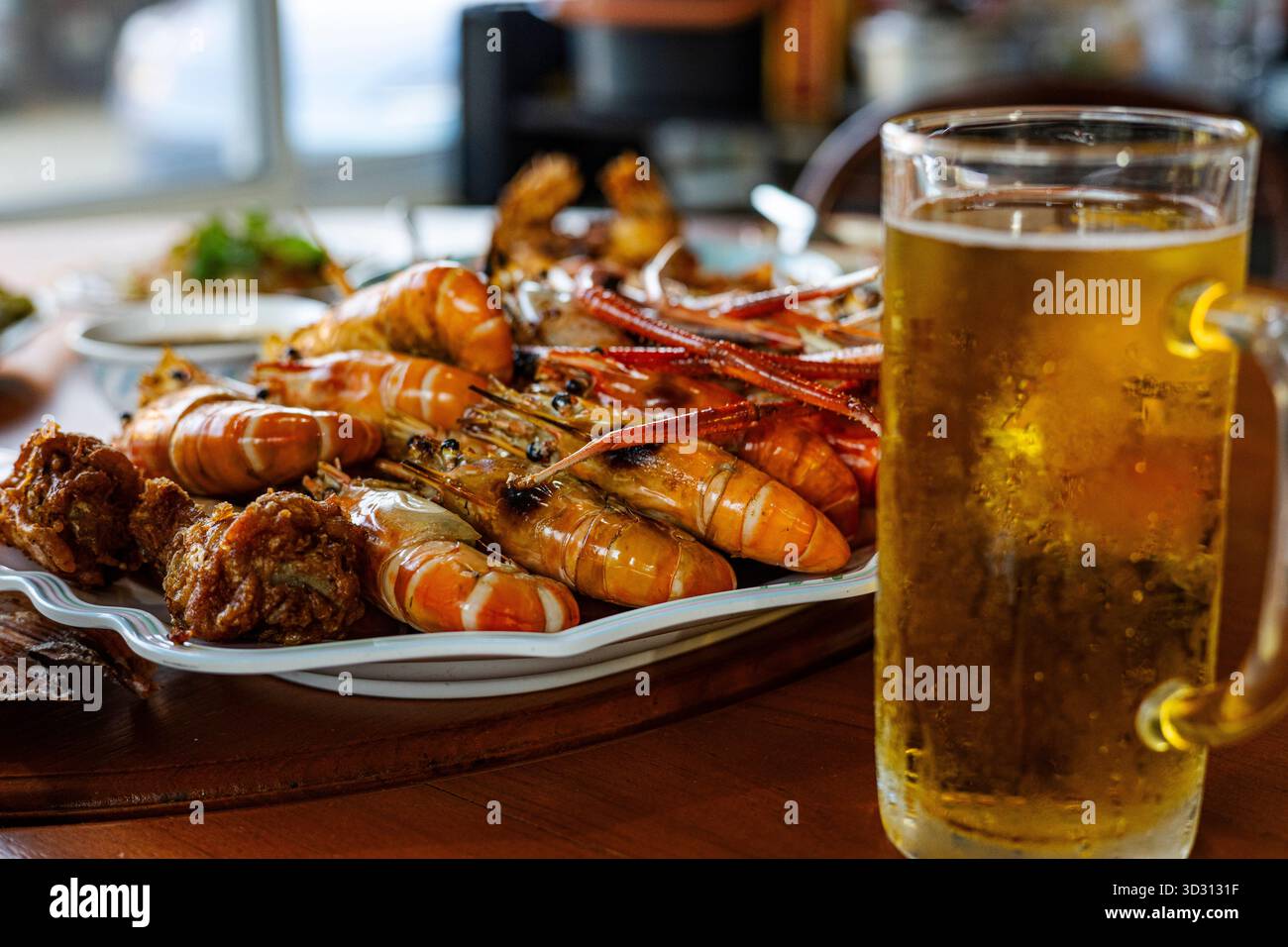 Crevettes grillées et bière froide à Party, Une photo dynamique de crevettes grillées grésillantes à côté d'une bière fraîche glacée lors d'une fête animée, parfaite pour les fruits de mer env Banque D'Images