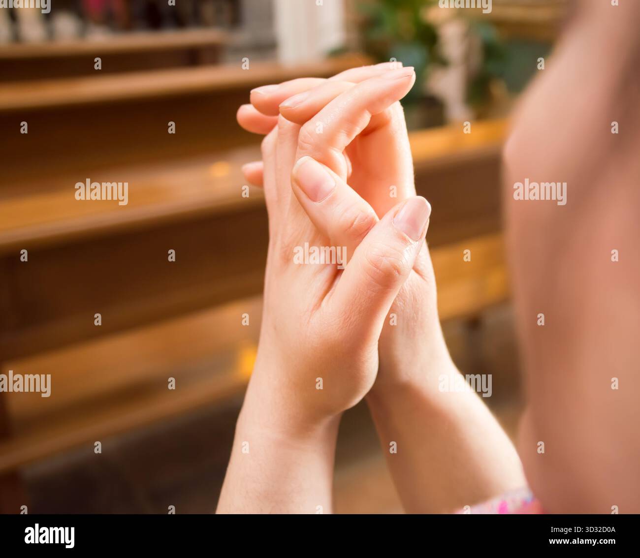 femme priant dans un banc à une église avec les mains jointes Banque D'Images