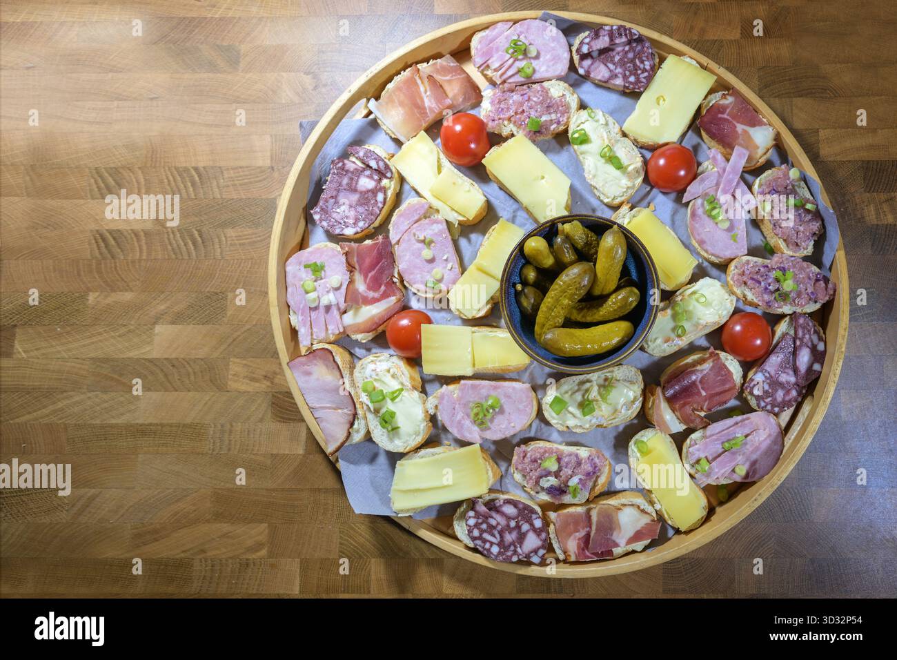 Petits sandwichs avec fromage, jambon et saucisse et un bol de cornichons sur un plateau rond, simple snack ou canapés de fête, vue de dessus, Banque D'Images