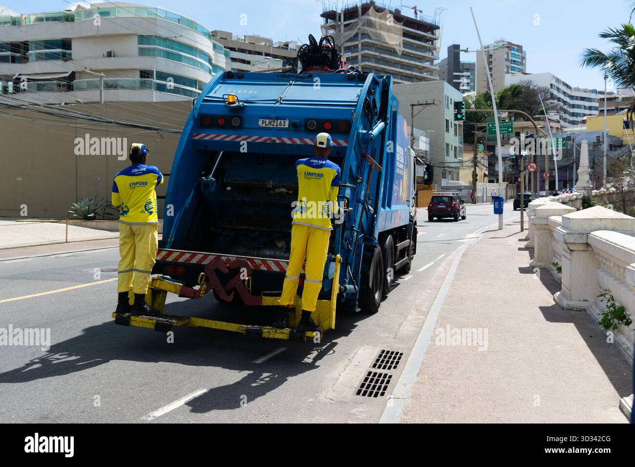 Salvador, Bahia, Brésil - 2 novembre 2025 : vue d'un camion à ordures bleu avec deux collecteurs sur une route urbaine dans la ville de Salvador, Bahia. Banque D'Images