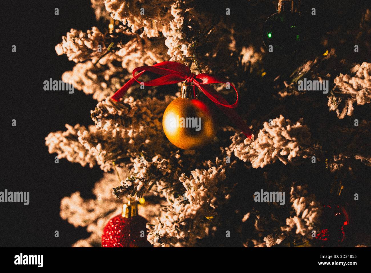 Gros plan de l'ornement de boule de Noël dorée accroché sur la branche d'arbre de Noël sur fond sombre Banque D'Images