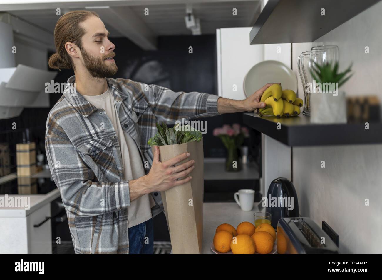 Homme déballer les légumes et les fruits dans la cuisine après avoir visité le magasin, achetant des produits frais Banque D'Images