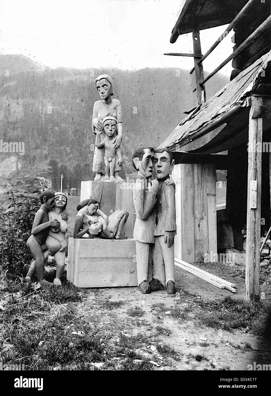 La photographie montre un groupe de quatre sculptures en bois de l'artiste expressionniste allemand Ernst Ludwig Kirchner. Les personnages sont disposés à l'extérieur devant un bâtiment rustique en bois, peut-être dans les Alpes près de Davos, en Suisse, où Kirchner a vécu plus tard dans sa vie. Kirchner, fondateur du groupe d'artistes Die Brücke, a créé une variété de sculptures en bois, les peignant souvent pour ajouter de la couleur et de l'expression. Ses sculptures ont été influencées par l'art africain et océanique « primitif » et se caractérisent par des formes simplifiées, angulaires et aplaties. Banque D'Images