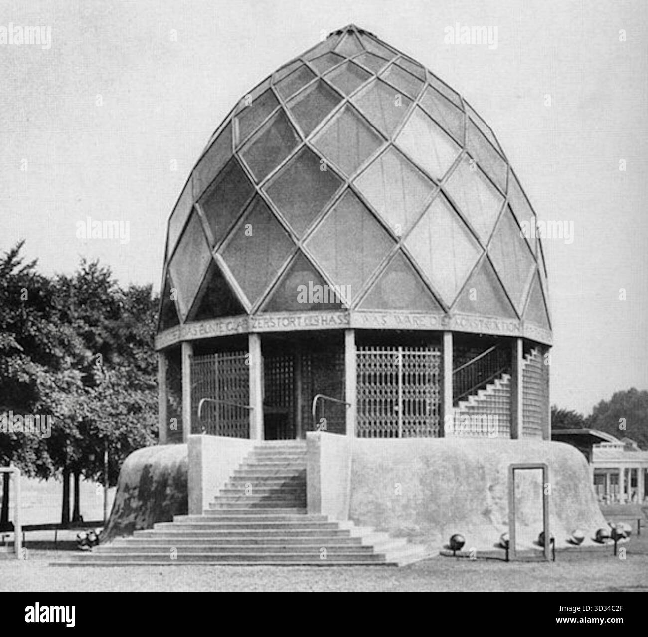 Bruno Taut - le Pavillon de verre était un bâtiment expressionniste - 1914 - le pavillon présentait un design circulaire avec un dôme prismatique à facettes sur une base en béton, ce qui lui donnait une qualité semblable à celle d'un temple. Bien que les photographies survivantes soient en noir et blanc, le bâtiment était de couleurs vives. Taut l'a décrit comme un « petit temple de beauté » avec un schéma de couleurs qui est passé du bleu foncé à la base au vert mousse, au jaune doré, et enfin un jaune pâle lumineux au sommet du dôme. Le dôme était composé d'une double couche de verre avec des prismes de verre coloré à l'intérieur et réfléchissant. Banque D'Images