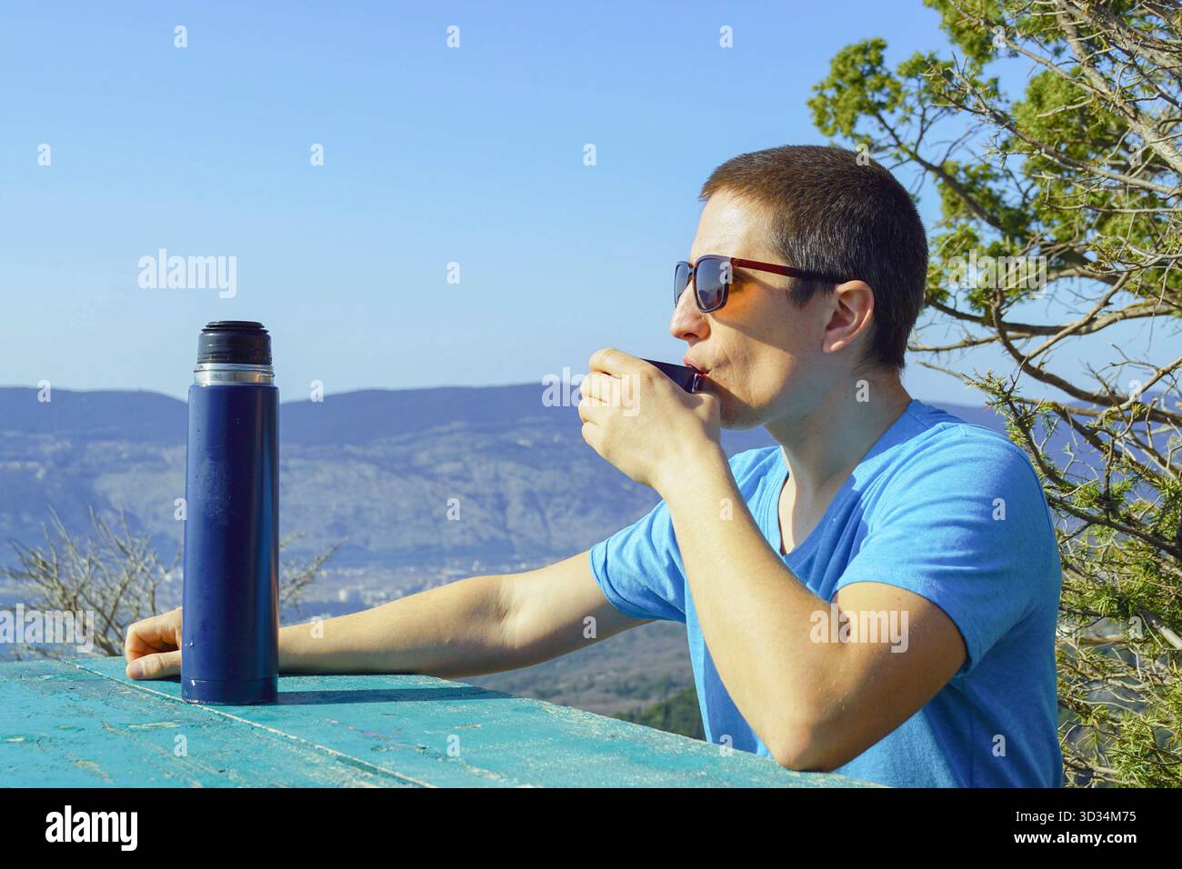 Touriste buvant dans une tasse de flacon thermal tout en profitant d'une vue panoramique sur la montagne. Symbolise l'appréciation des pauses scéniques et la pause du point de vue. Banque D'Images