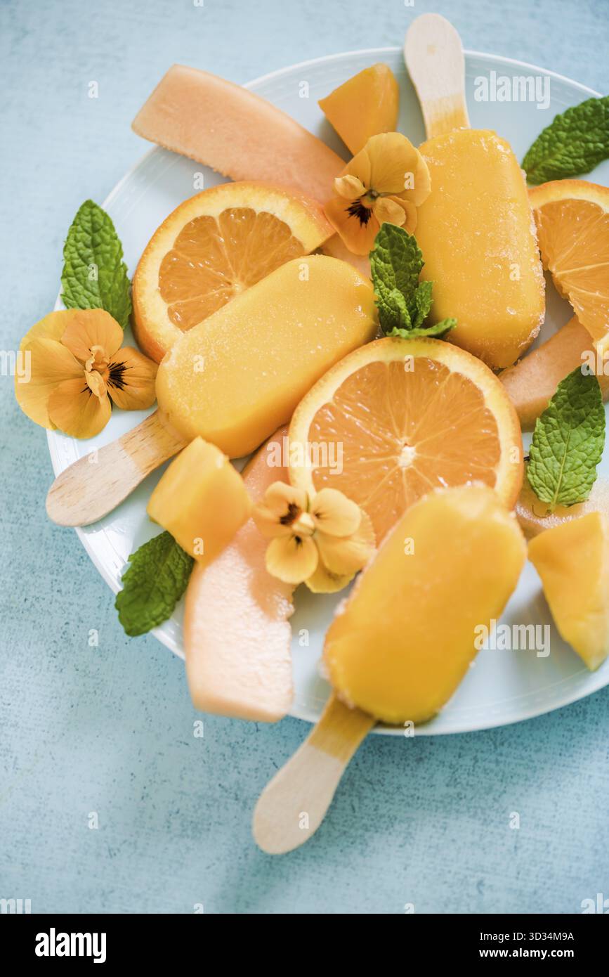 Traiter l'été des sucettes orange avec fruits frais et fleurs comestibles Banque D'Images