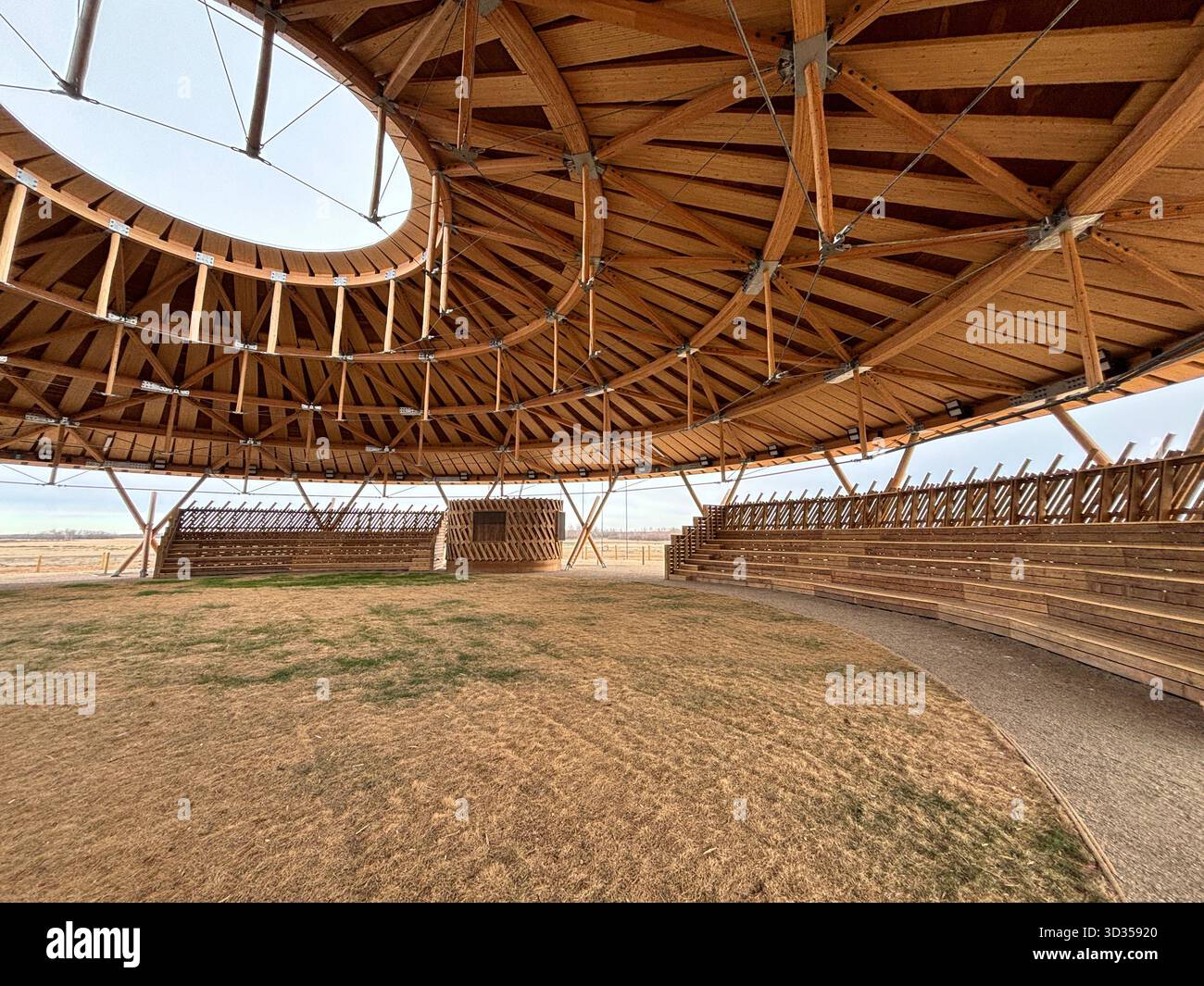 Amphithéâtre en bois avec un toit en bois large et des sièges en gradins sur une réserve indigène, situé contre de vastes prairies, symbolisant le design durable. Banque D'Images