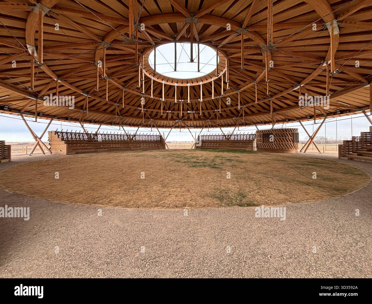 Amphithéâtre en bois avec un toit en bois large et des sièges en gradins sur une réserve indigène, situé contre de vastes prairies, symbolisant le design durable. Banque D'Images