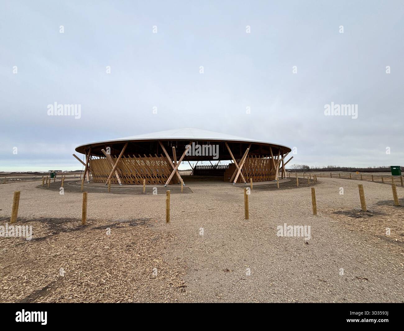 Amphithéâtre en bois avec un toit en bois large et des sièges en gradins sur une réserve indigène, situé contre de vastes prairies, symbolisant le design durable. Banque D'Images