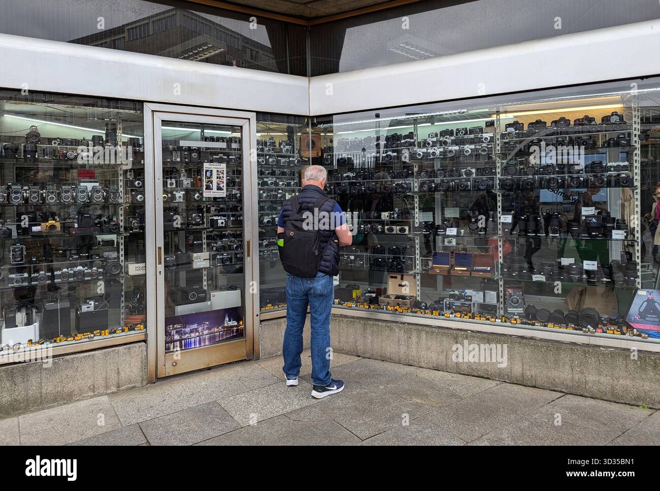 Cologne, Allemagne - 26 septembre 2025 : un homme examine une collection d'appareils photo vintage exposés dans un magasin d'antiquités. Banque D'Images