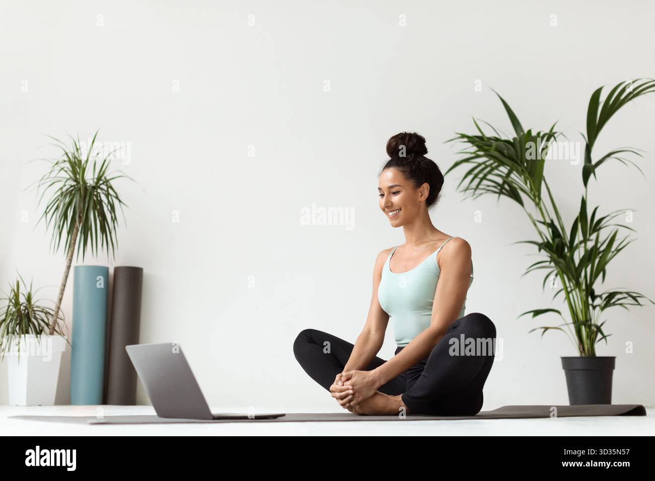 Pratique du yoga à la maison avec un ordinateur portable, une jeune femme profite de sa séance de méditation Banque D'Images