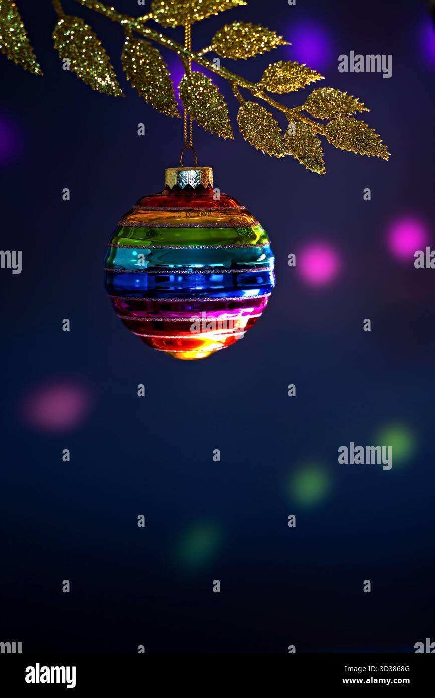 Couleurs arc-en-ciel de boule de Noël suspendues sur la branche dorée Banque D'Images