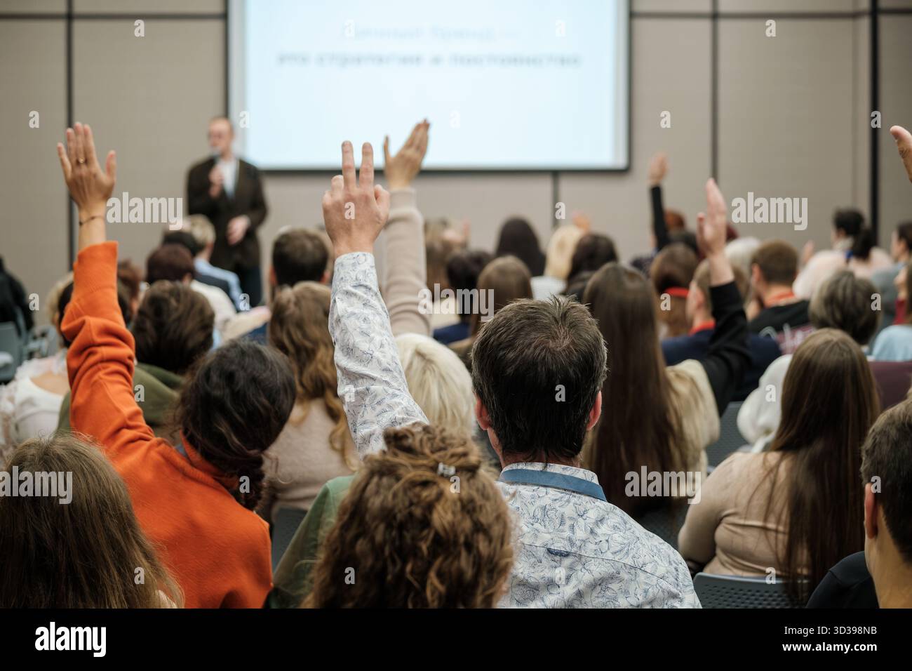 Le public lève la main pendant la présentation de la conférence dans une grande salle de conférence. L'intervenant à l'avant-garde donne la parole au fur et à mesure que les participants participent, signalant ainsi l'engagement et la collaboration en matière d'apprentissage Banque D'Images