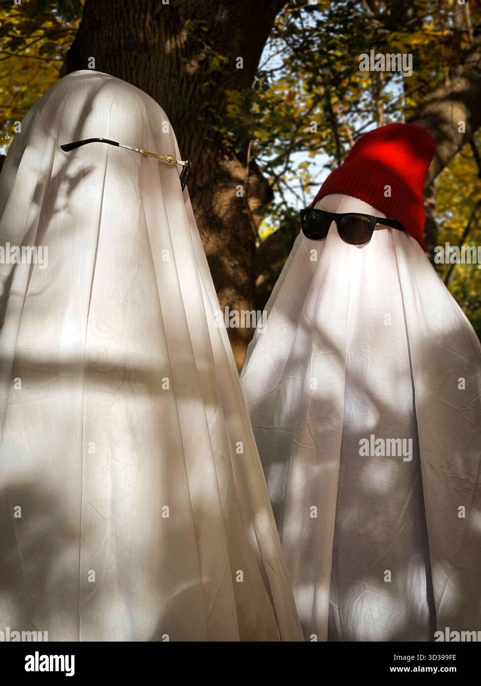 Deux fantômes ludiques à la lumière du soleil, concept de plein air surréaliste pour les tendances des médias sociaux d'Halloween 2025. Photo de haute qualité Banque D'Images