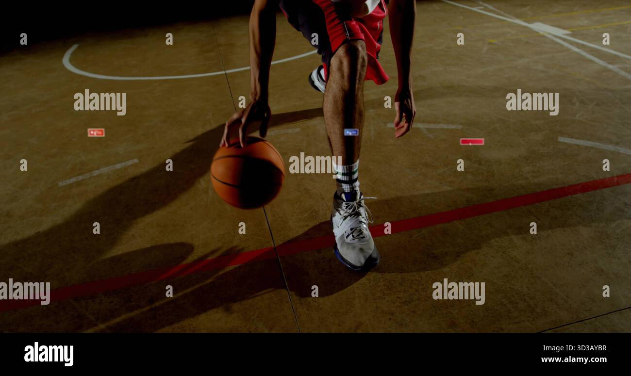 Joueur de basket-ball en uniforme rouge dribble basket-ball sur un terrain de gymnastique avec des lignes blanches rouges, des ombres Banque D'Images