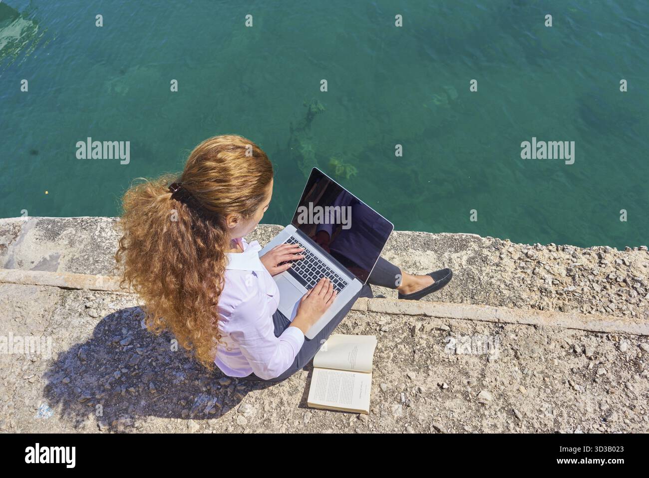 Nomade numérique, femme d'affaires créative indépendante, éditeur, romancier, écrivain ou conférencier travaillant avec un ordinateur portable mobile et livre au bord de la mer pendant le soleil Banque D'Images