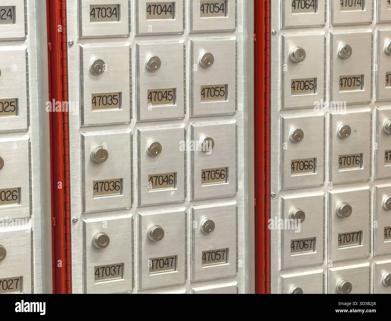 Calgary, Alberta, Canada. 16 mai 2025. Un gros plan capture une grille de boîtes aux lettres privées, leurs portes argentées et des numéros noirs créant un fonctionnel Banque D'Images