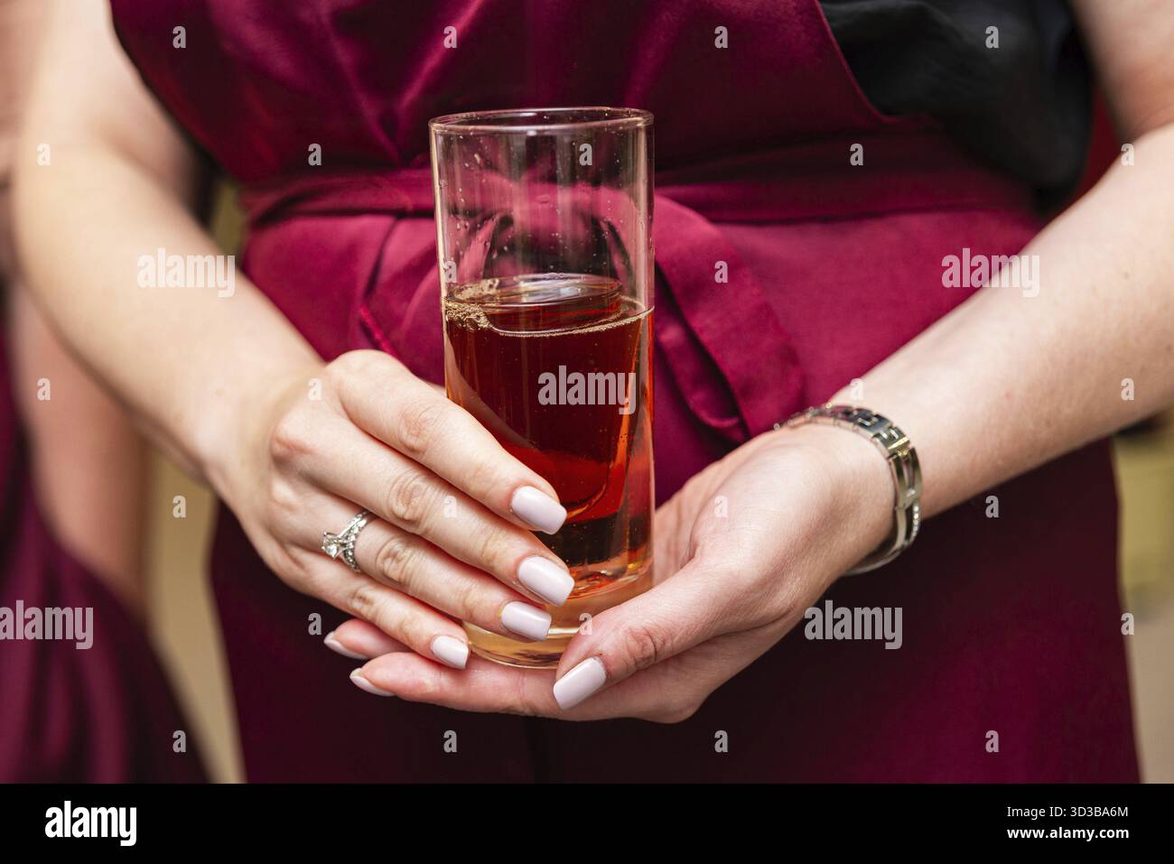 Nourriture, gros plan d'une femme dans un tablier rouge tenant un verre de boisson glacée foncée, éventuellement du soda ou du thé, pendant un atelier Banque D'Images