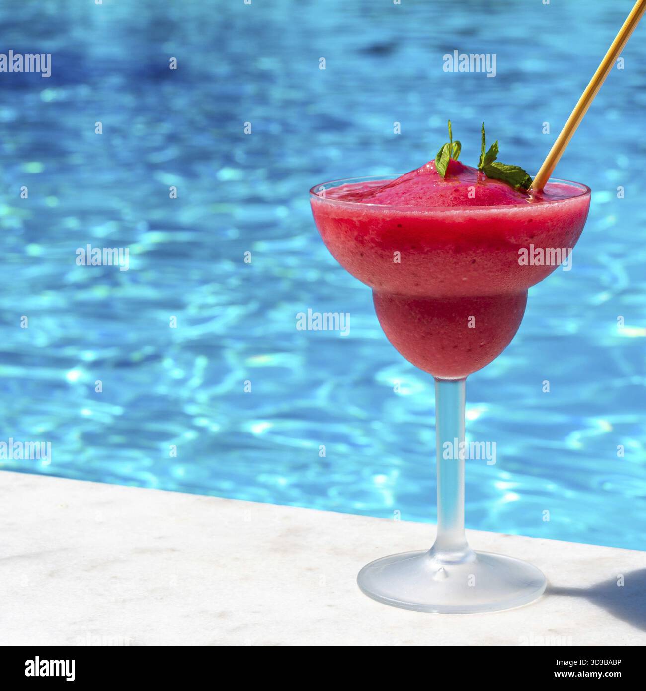 Un daiquiri aux fraises dynamique au bord d'une piscine rafraîchissante par une journée ensoleillée, évoquant un sentiment de détente et d'évasion tropicale Banque D'Images