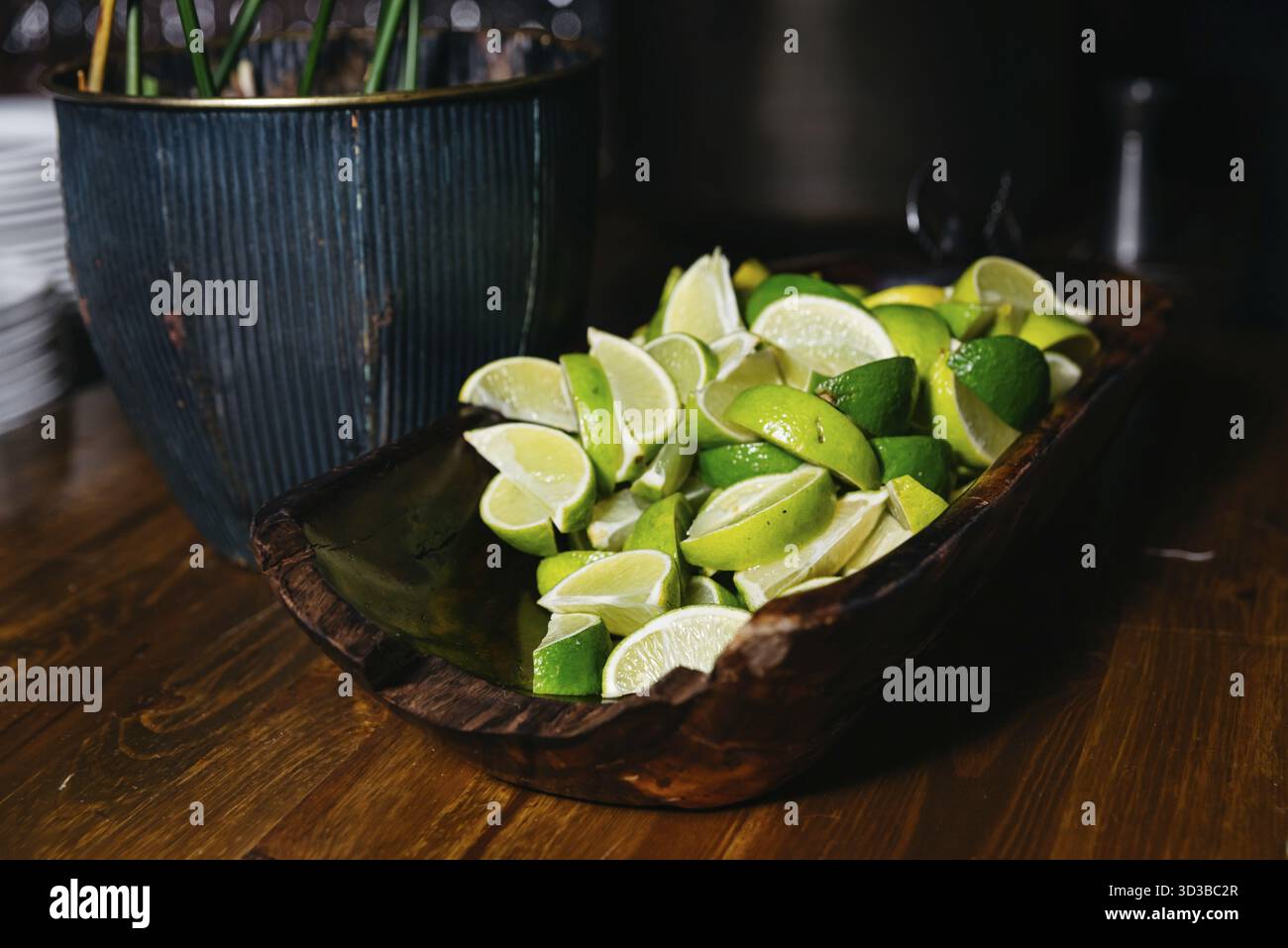 Nourriture, Un tas de quartiers de citron vert fraîchement coupés servis dans un bol en bois sculpté, idéal pour les cocktails, les garnitures alimentaires, ou l'utilisation de buffet Banque D'Images