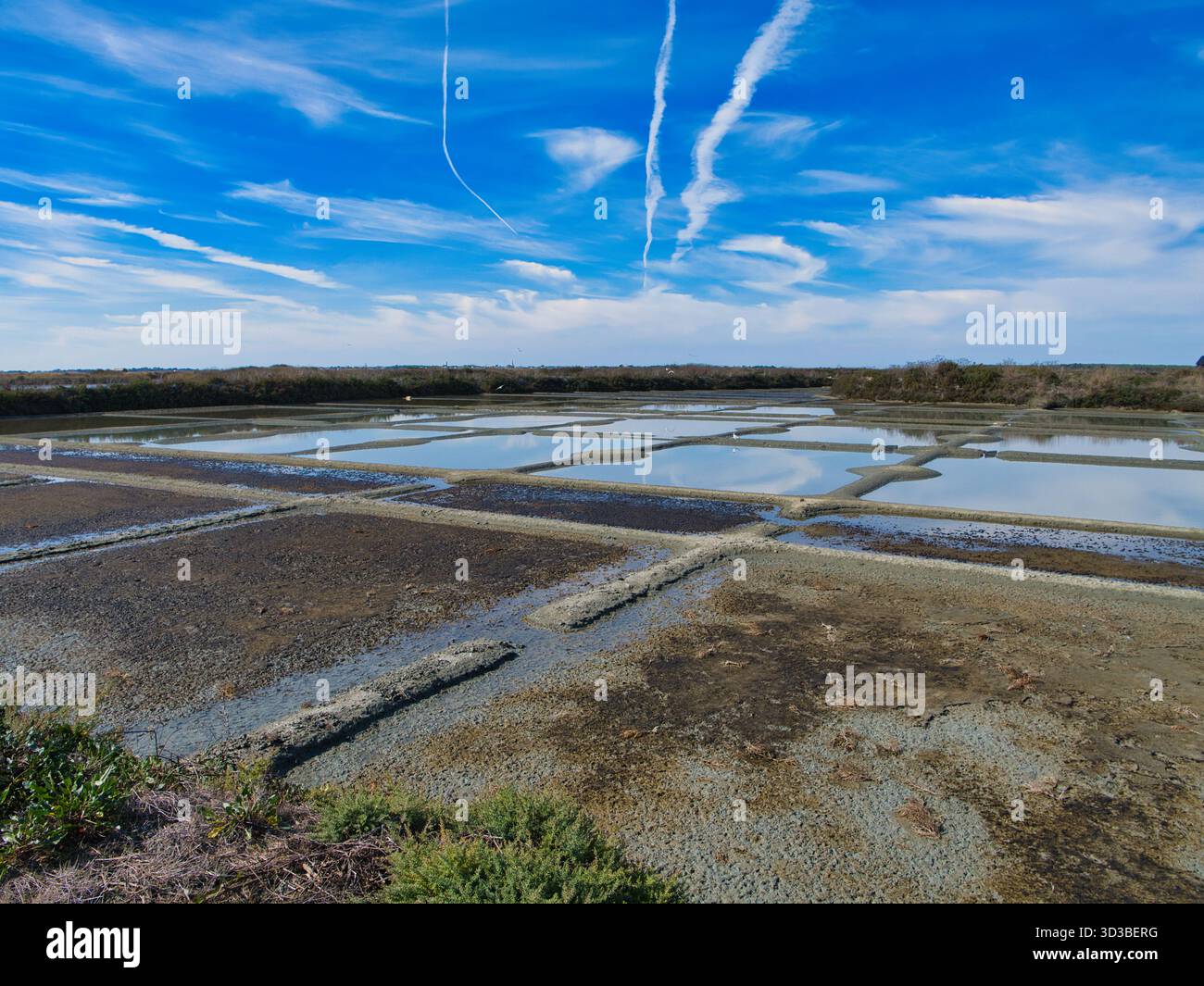 Guérande, France - 01 oct 2025 : les étangs d'évaporation géométriques reflètent un ciel éclatant aux marais salants de Guérande en France, capturant la production traditionnelle de sel marin à midi. Banque D'Images