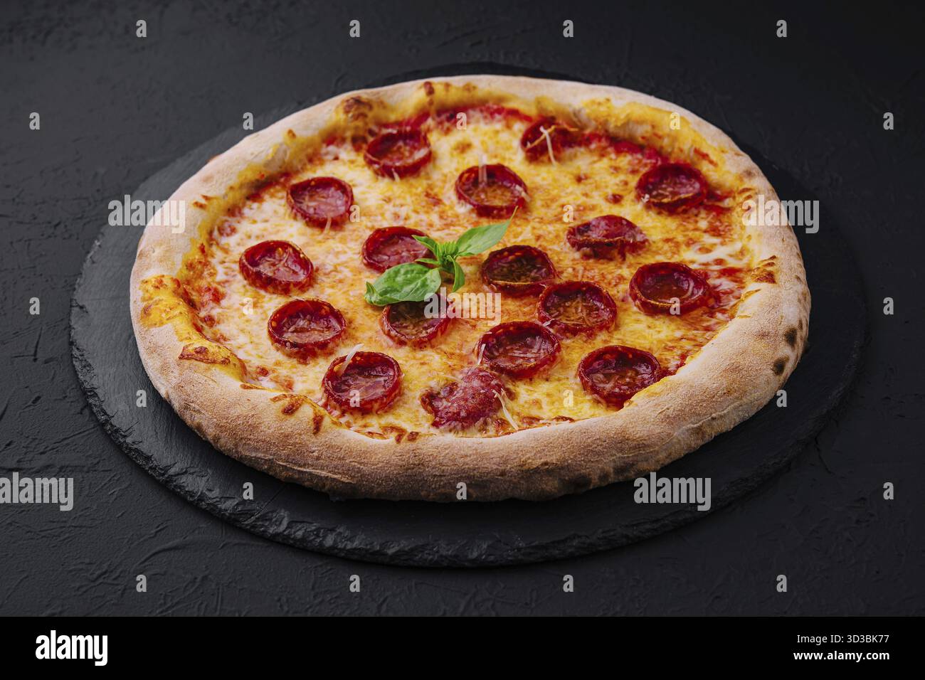 Nourriture, pizza au pepperoni au basilic et au parmesan sur une assiette en pierre noire Banque D'Images
