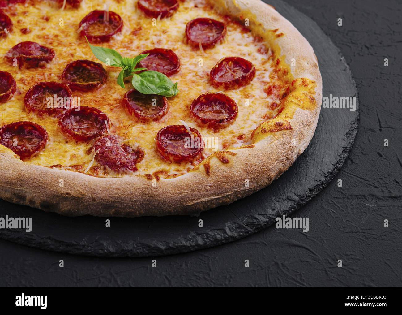Nourriture, pizza au pepperoni au basilic et au parmesan sur une assiette en pierre noire Banque D'Images