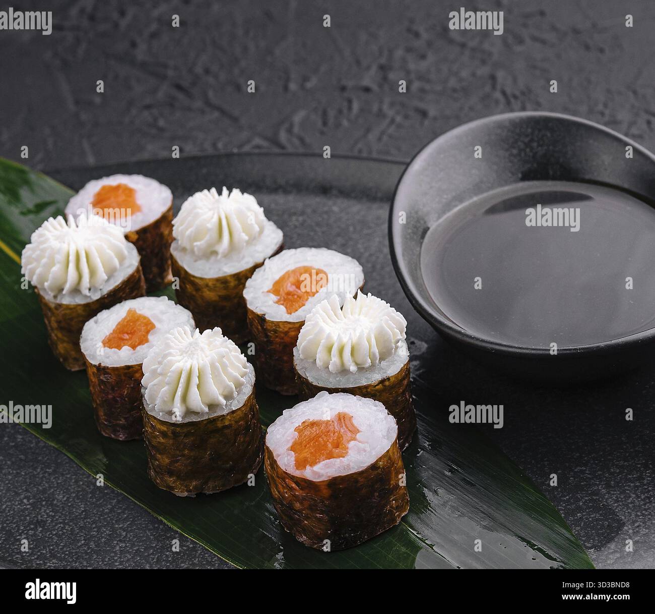 Nourriture, sushi avec fromage Philadelphie et saumon sur assiette asiatique noire Banque D'Images