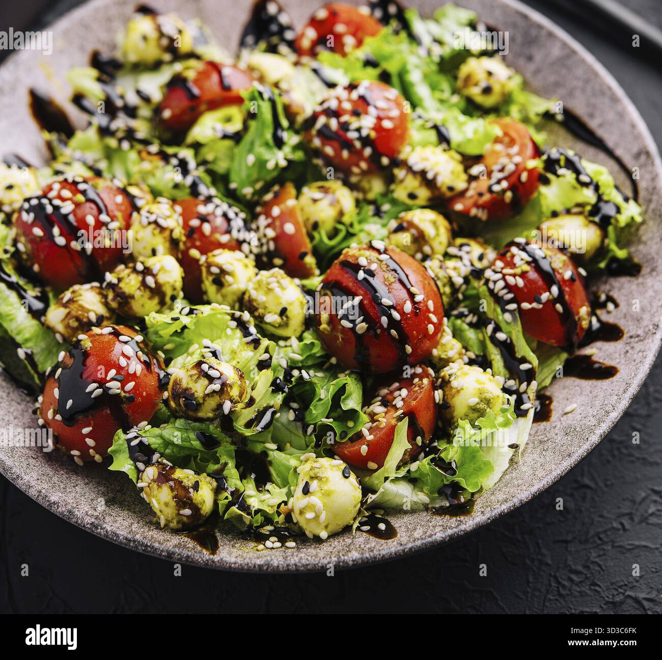 Nourriture, salade verte à base de tomates, boulettes de mozzarella au fromage et sésame sur assiette Banque D'Images
