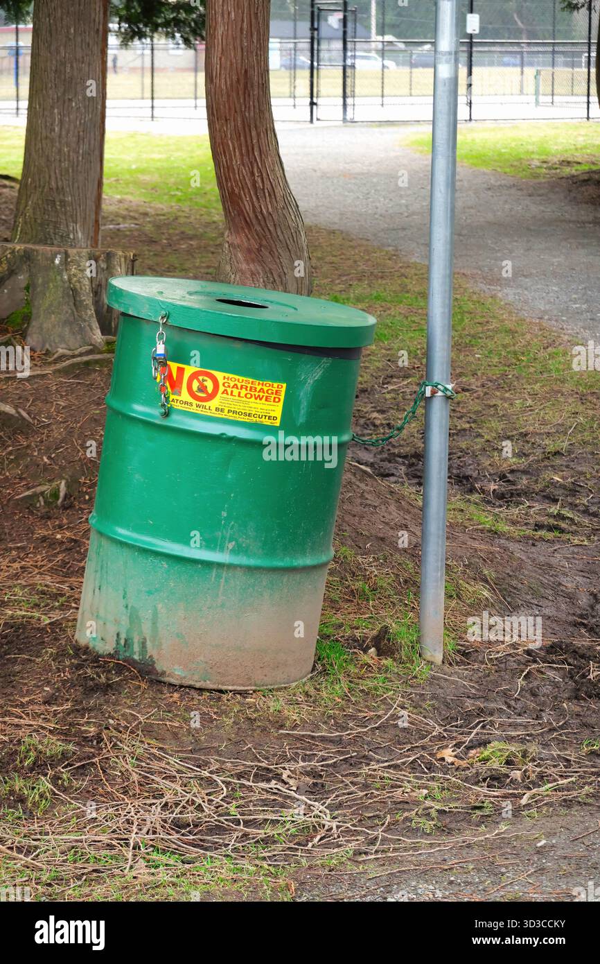 Poubelle ou poubelle enchaînée à un poteau dans un parc avec un autocollant indiquant « pas d'ordures ménagères autorisées - les contrevenants seront poursuivis » Banque D'Images