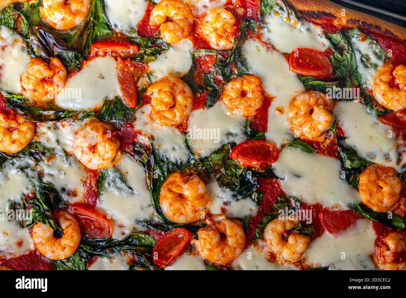 Pizza aux crevettes, tomates et épinards, gros plan. Fond méditerranéen de texture de pizza. Photo de haute qualité Banque D'Images