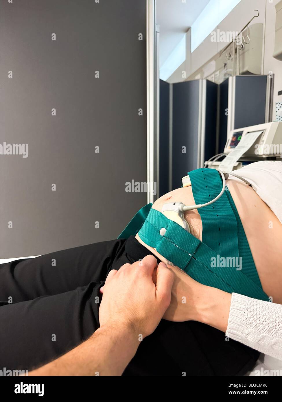 Femme enceinte tenant la main du partenaire pendant la surveillance foetale Banque D'Images