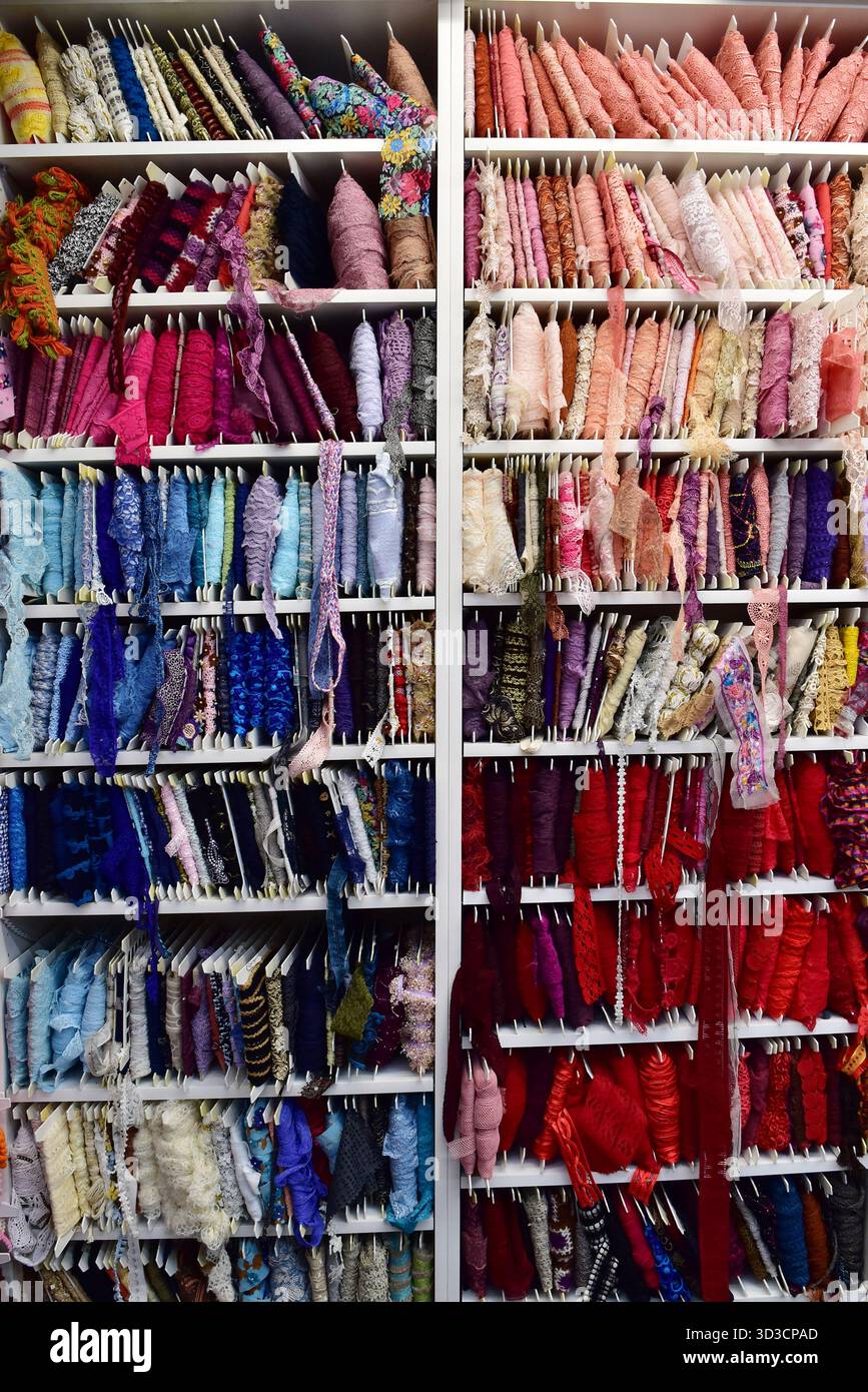 Rangées et rangées de dentelle complexe, ruban et garniture, méticuleusement organisées par couleur. Un instantané vibrant d'un magasin de fournitures textiles ou artisanales Banque D'Images