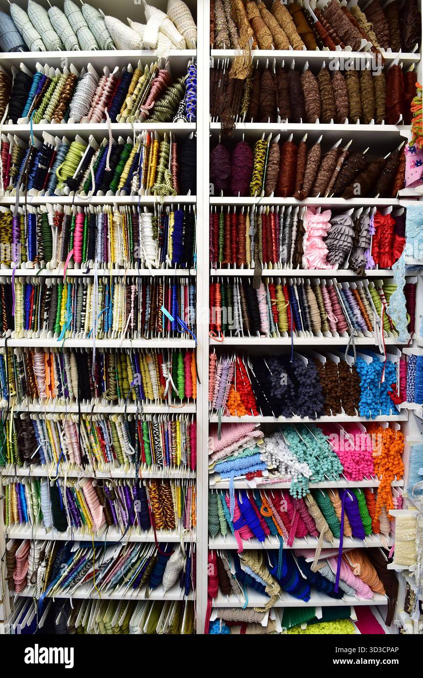 Rangées et rangées de dentelle complexe, ruban et garniture, méticuleusement organisées par couleur. Un instantané vibrant d'un magasin de fournitures textiles ou artisanales Banque D'Images