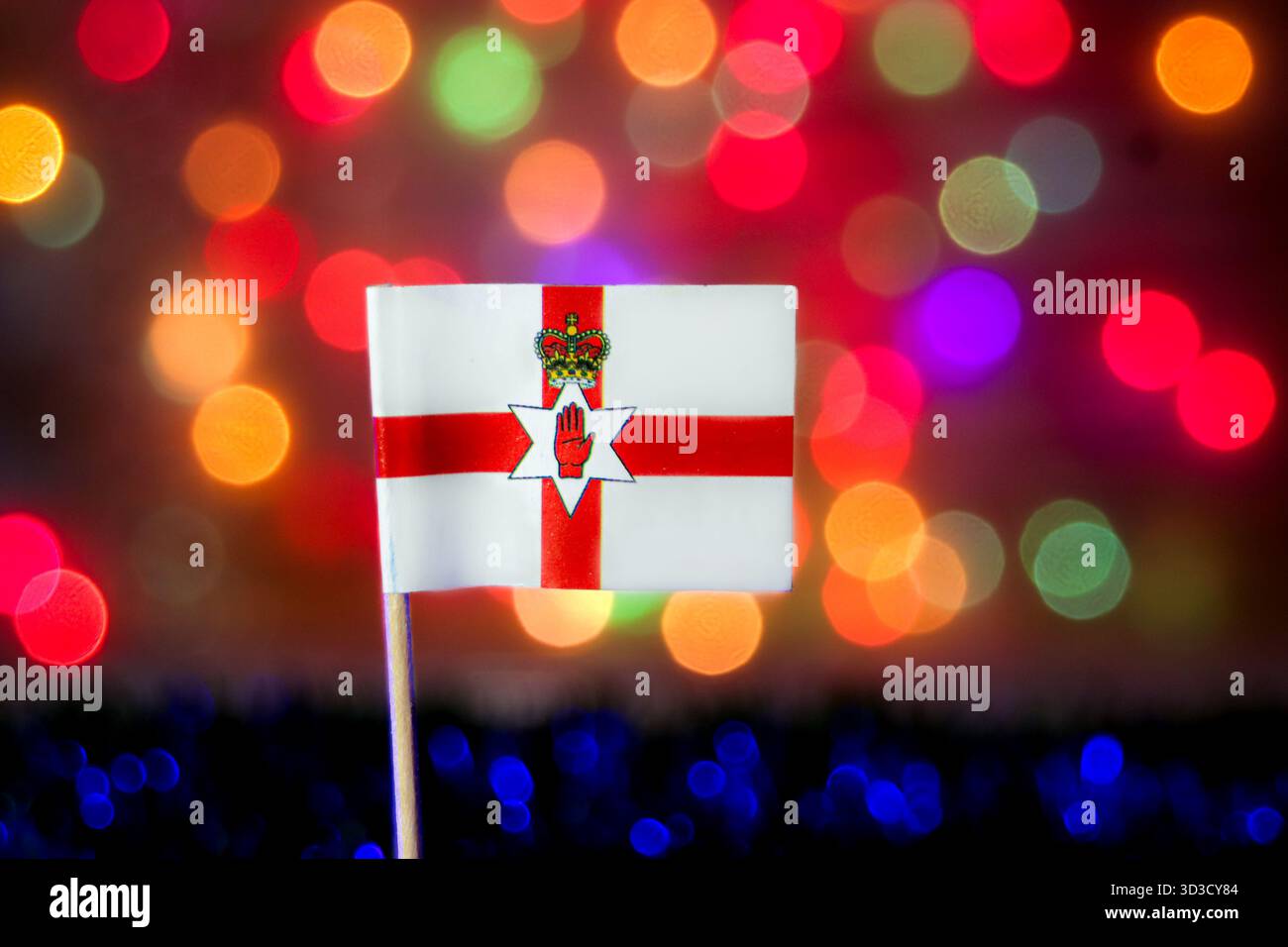 Drapeau d'Irlande du Nord contre le bokeh coloré. Idéal pour la fierté nationale, les célébrations, le tourisme au Royaume-Uni, et les événements associés à la fête de Patrick. Banque D'Images