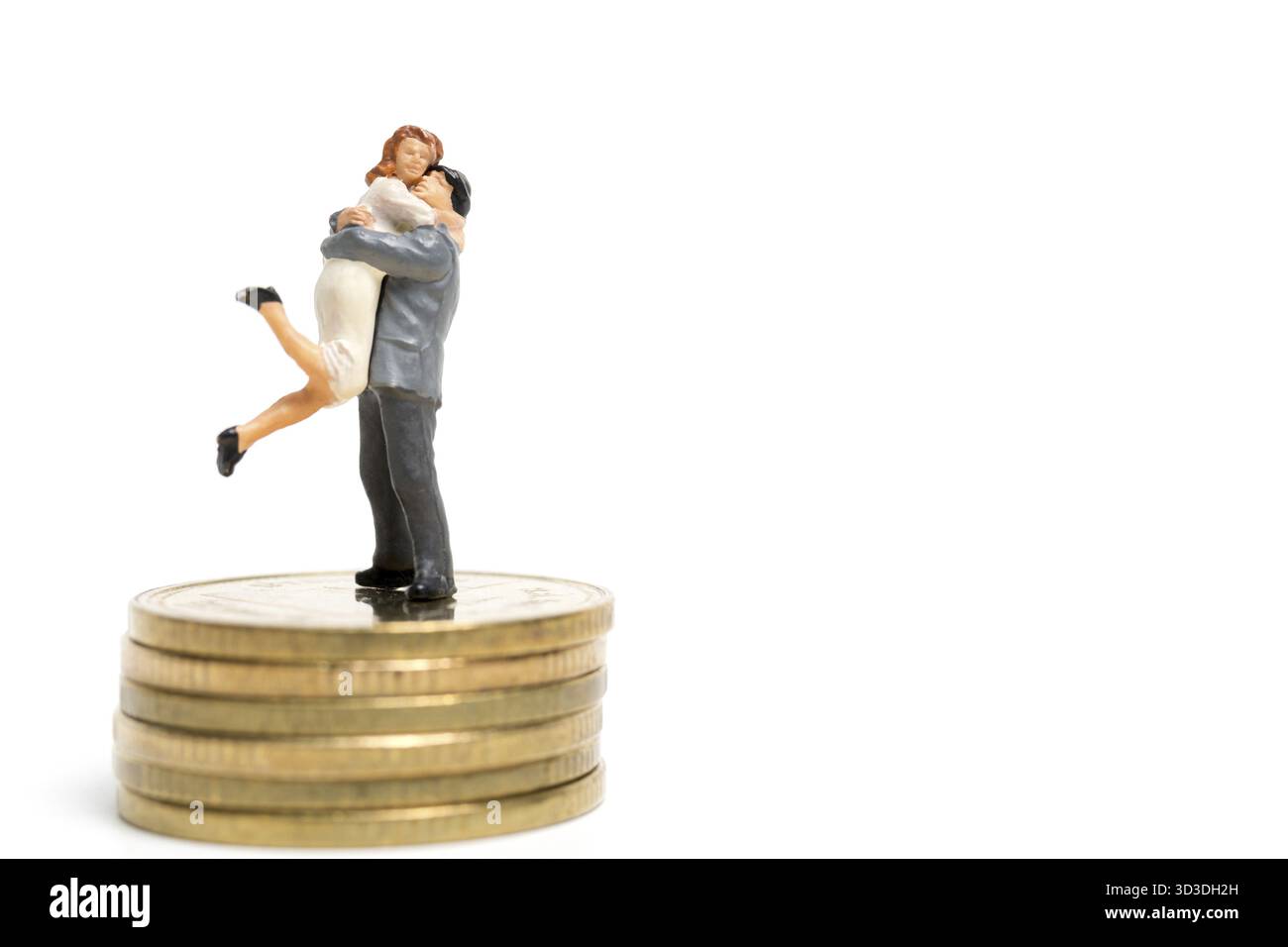 Personnages miniatures : couple serrant debout sur la pile de pièces de monnaie, de l'argent et des concepts financiers Banque D'Images