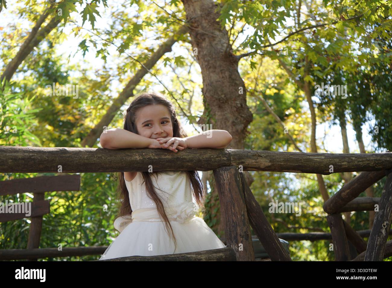 Une petite fille de cinq ans aux cheveux très longs admire la nature au parc Fodele en Crète - elle regarde vers le bas depuis le pont en bois de la rivière Pantomantris. Banque D'Images