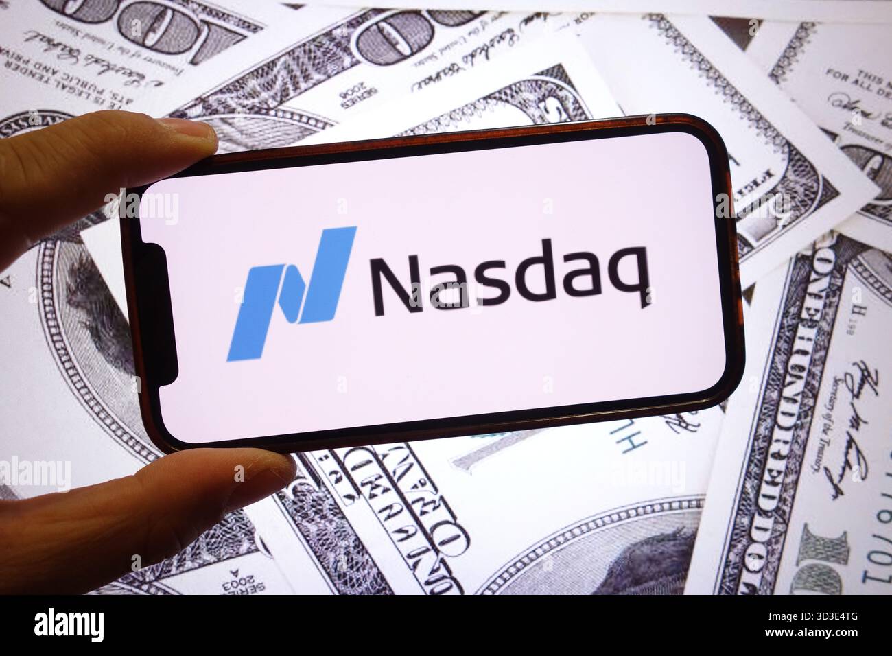 Dans cette illustration photo, le logo de la société Nasdaq est affiché sur un écran de smartphone avec les billets de banque en dollars des États-Unis en arrière-plan. Banque D'Images